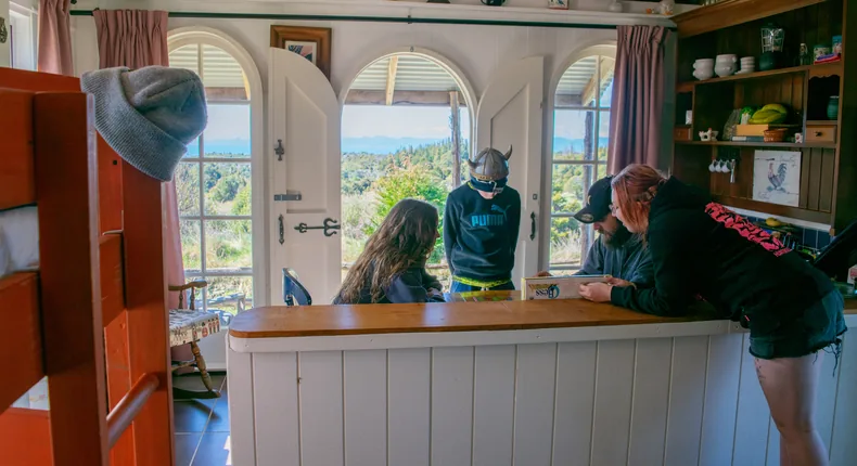 A family playing chess inside Pioneer Hut, the arched doors open to the valley